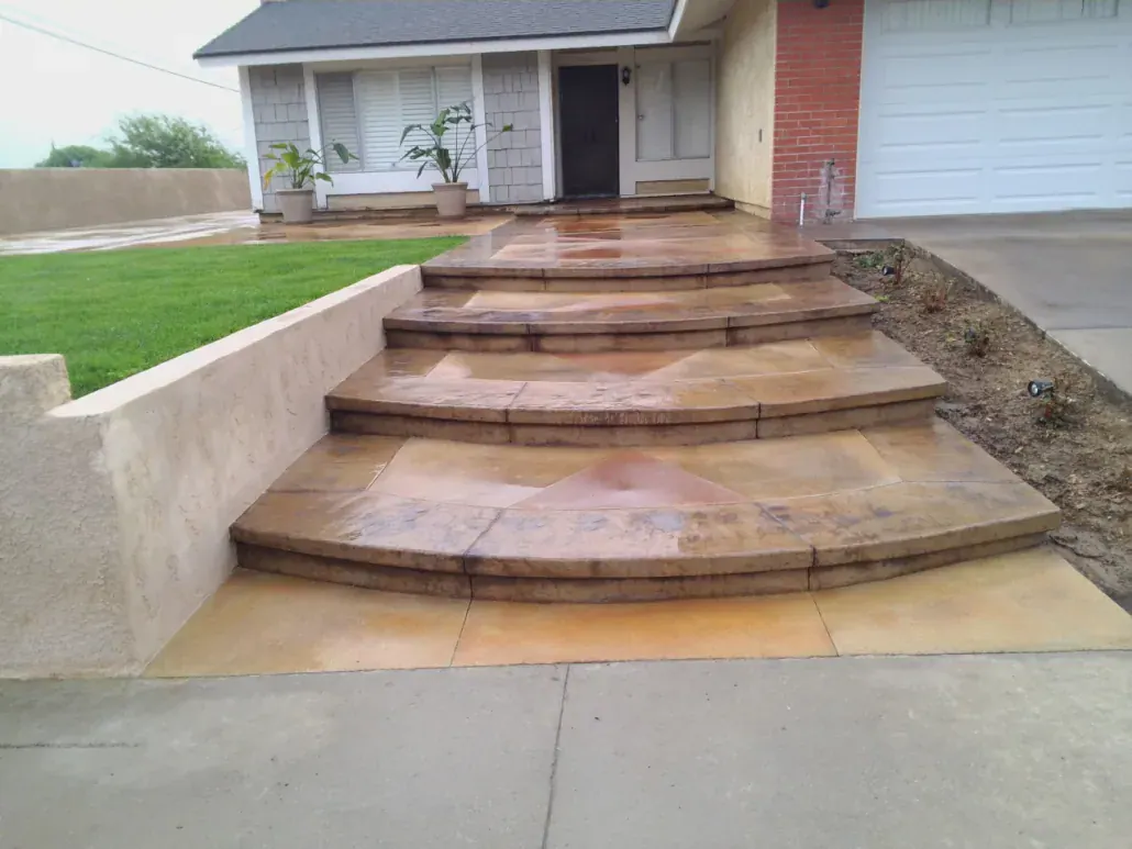 Curved stained-concrete entry steps with a low retaining wall planter leading to a front door