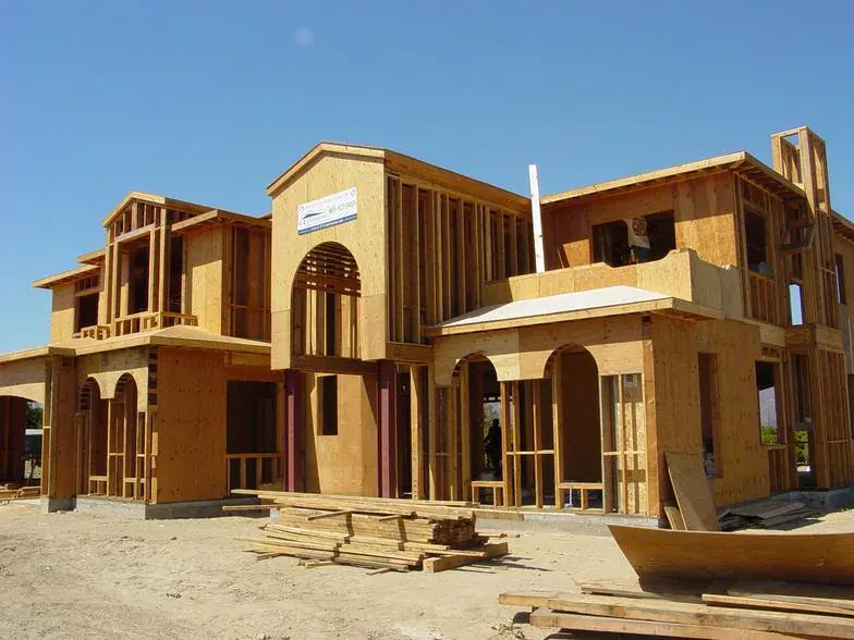 Wood framing for a large two-story custom home with arched window openings and a tower element