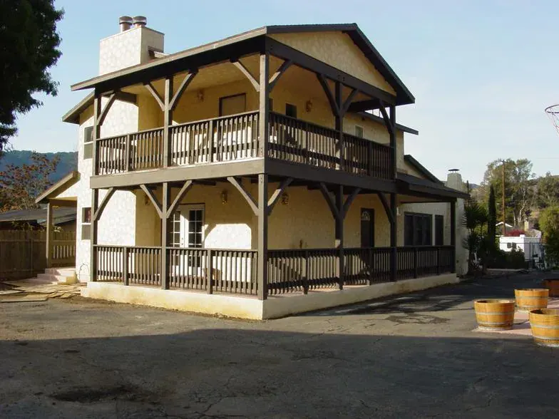 Two-story home with covered wood balconies on both levels and a stone chimney