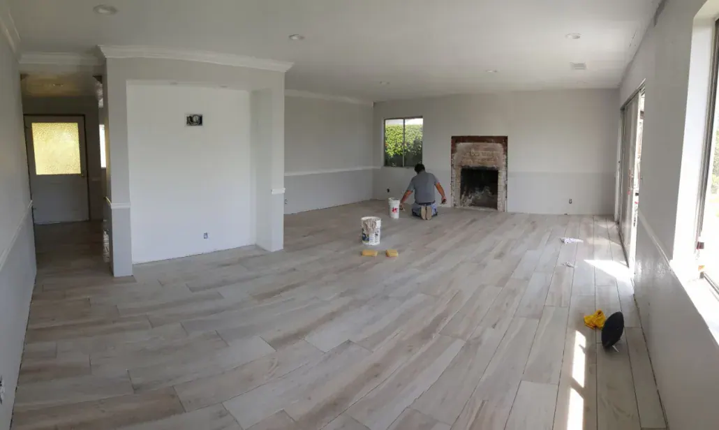 Wood-look tile being installed across an open family room during a remodel, fireplace still in progress