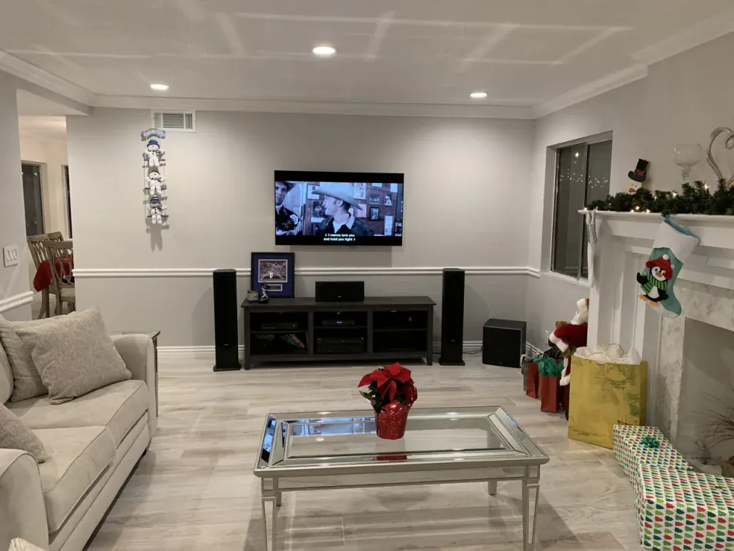 Finished living room with white wainscoting, new flooring and a mantel wall after an interior remodel