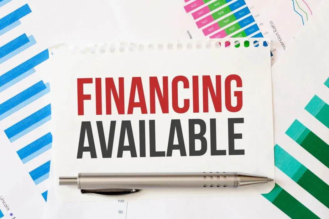 Notepad reading Financing Available beside a pen and printed charts